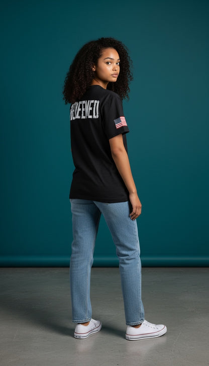 Model wearing a black Forged By God cotton t-shirt with a distressed REDEEMED back print and American flag sleeve detail.